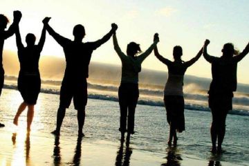 photo of a team joined together on a beach at sunset