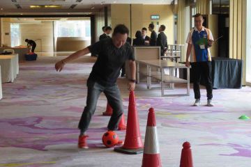 man dribbling soccer ball in goall team building activity