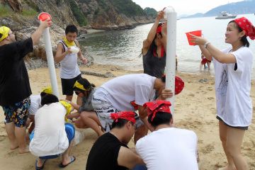 employees collaborate to complete breakthrough team building activity on a beach