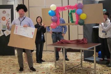 team posing with their arms up out of the box team building activity