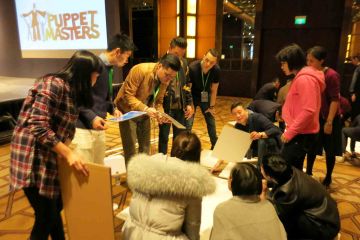 team collaborate to construct a puppet creative team building activity