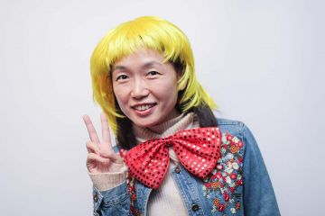 woman wearing blond funny wig and a big bow tie in the picture fun team building activity