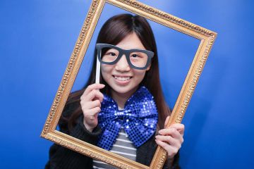 woman holding a frame to her face unny wig and a big bow tie in the picture fun team building activity