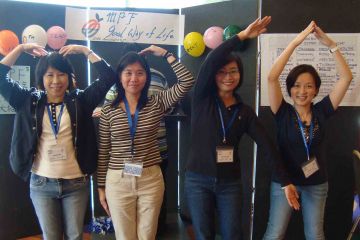 team posing with their arms up out of the box team building activity