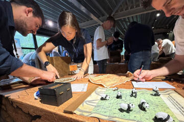 Participants solving puzzles together during the Passport to Adventure indoor team building activity.