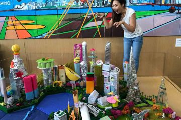 woman posing next to a model of the city team building activity city build